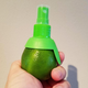 Hand holding up a lime with a citrus sprayer screwed into it